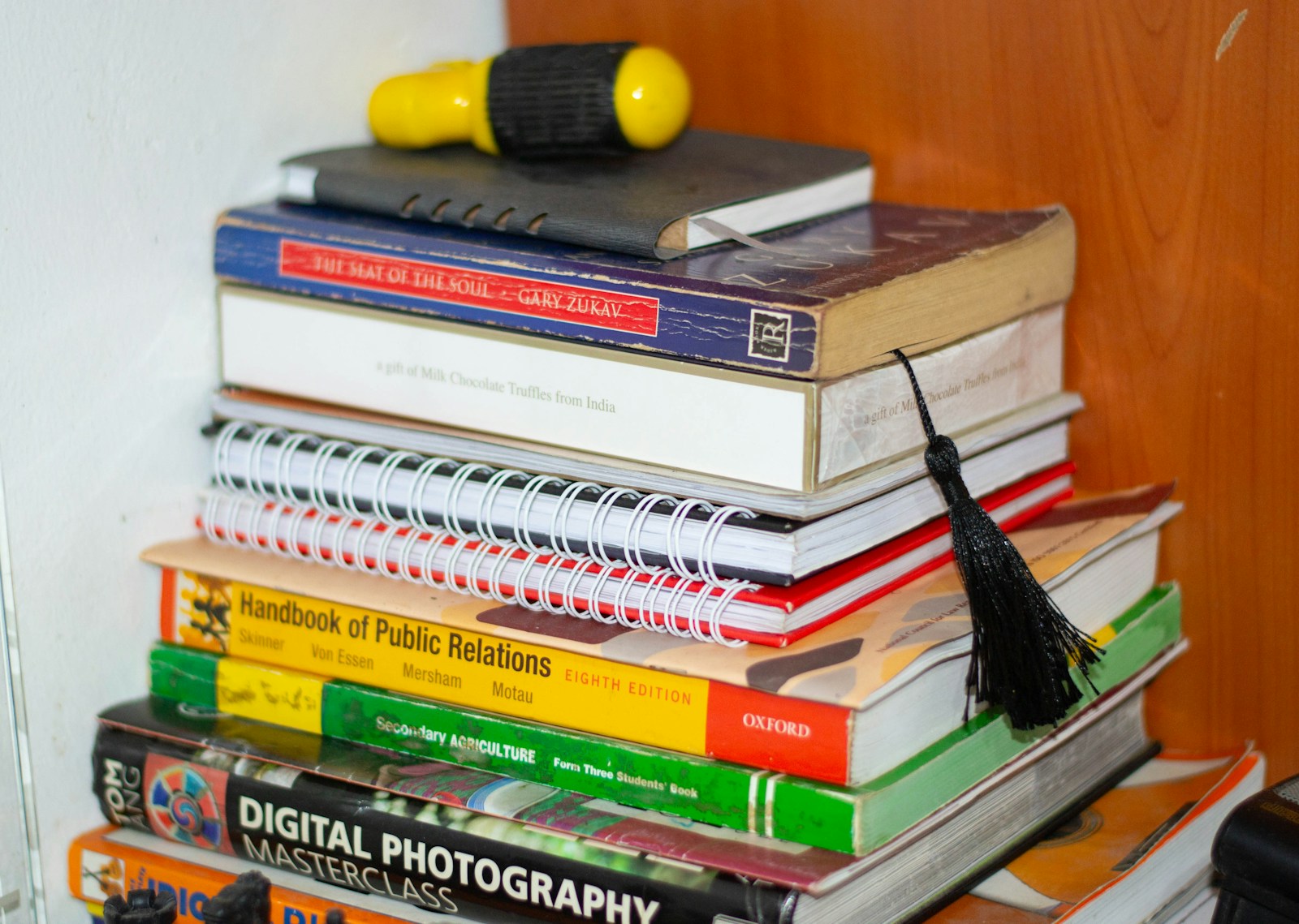 Stack of books with a yellow object on top.